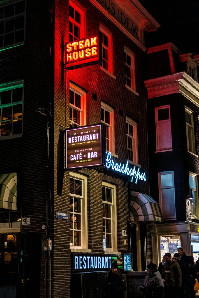 Night view of an illuminated steakhouse and restaurant in Amsterdam with neon lights.